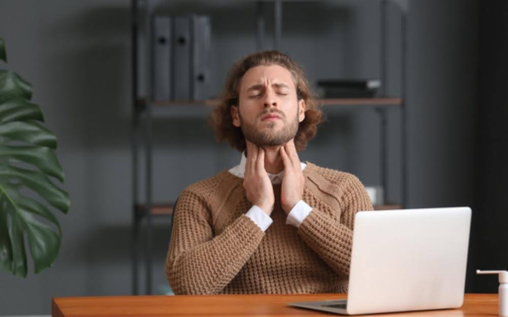 Mężczyzna odczuwający ból gardła w trakcie pracy